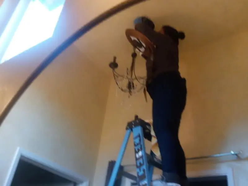 Electrician installing a chandelier in a Solon residence